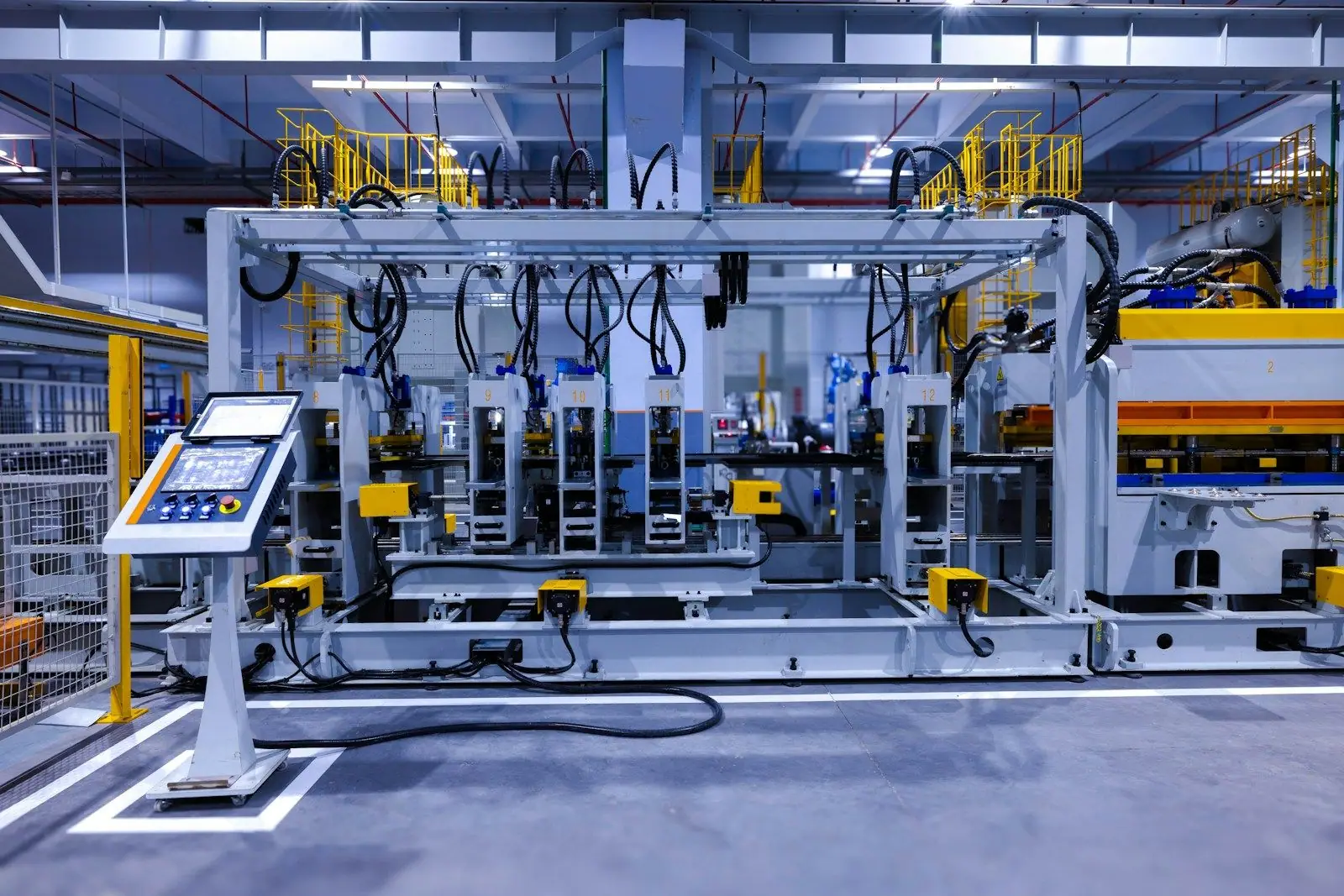 An automated production line with an operator touchscreen panel beside the machine